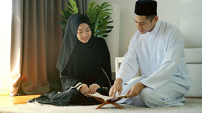 Muslim man and woman reading Quran at home